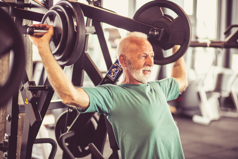Senior man lifting weights at the gym