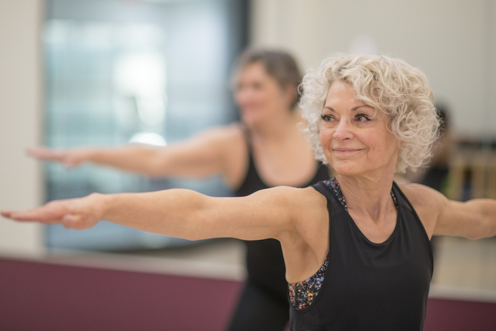 Older adult woman stretches in balance exercise group class.
